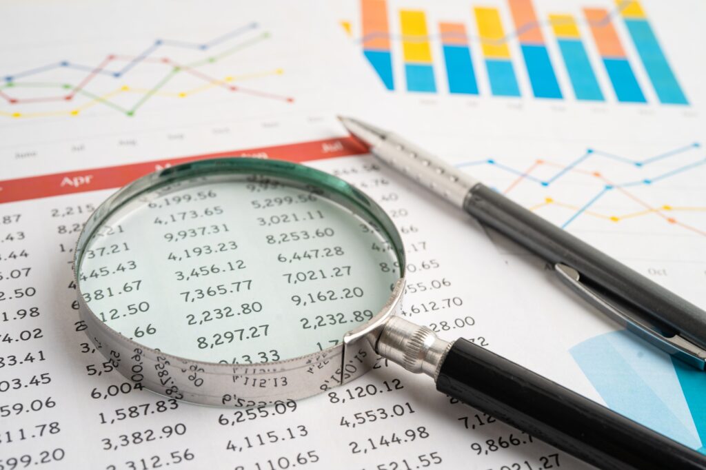 Magnifying glass on spreadsheet and graph paper. Financial data economy, Business.